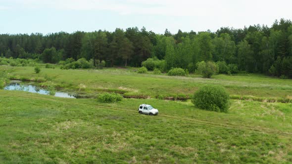 Aerial View of a Car Driving in Nature Near the River alt