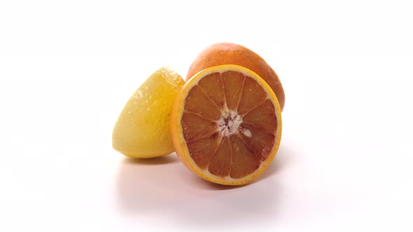 Fresh Cutted Red Oranges and Lemon are Spinning on White Background alt