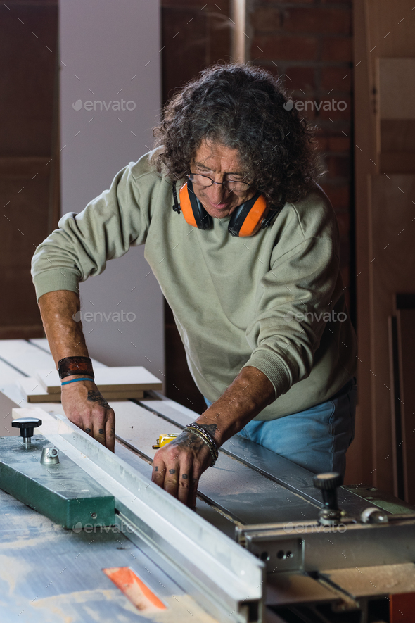Carpenter cutting wood with circular saw in joinery Stock Photo by