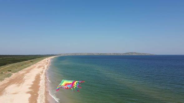 Rainbow a Multicolored Kite Flies Over the Sea in Summer Taken on Drone alt