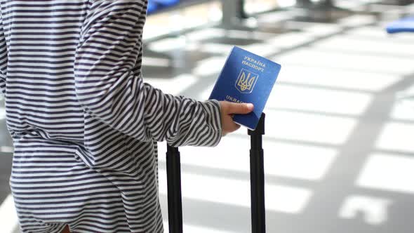 Sad Ukrainian Child Refugee at the Airport with a Passport in His Hands alt