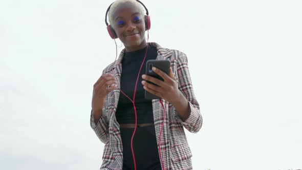 Young woman with headphones and smartphone listening music alt