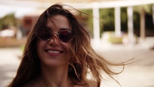 Joyful Woman in Sunglasses Walking in the Park with Palm Trees Holding Yellow Cone Ice Cream alt