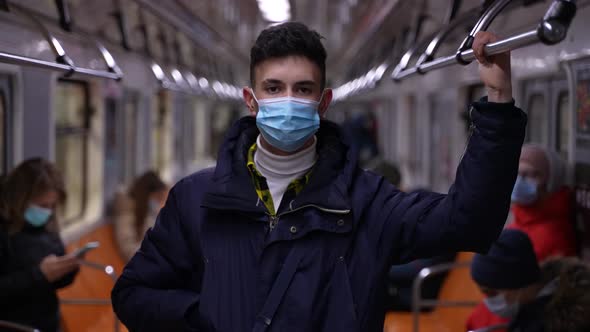 Teenager in Face Mask and Jacket Riding in Subway alt