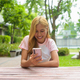 Portrait of beautiful Asian girl with blonde hair smiling using phone outdoors while sitting - PhotoDune Item for Sale