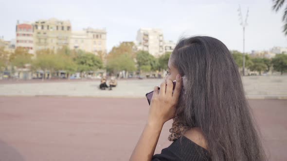 Young black woman in the middle of the street, picks up her phone alt