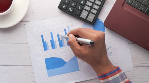 Man Hand with Pen Analyzing Bar Chart on Paper  alt