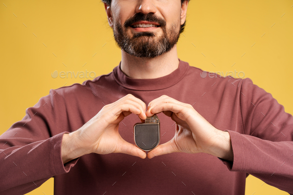 Portrait of young man showing pacemaker in two hands, isolated in ...