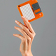 Crop female hand holding orange floppy disk in studio - PhotoDune Item for Sale