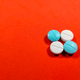 A white and blue medicine pills on red background  - PhotoDune Item for Sale