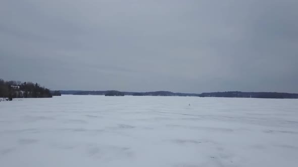 Aerial View of Snowmobile Rider Driving over Frozen Lake in Winter 1