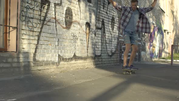 Vigorous Young Person Riding Skateboard Near Graffiti Wall in The Street, Hobby alt