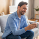 Man Sitting on Couch Looking at Phone and Smiling - PhotoDune Item for Sale