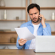 Concerned Man Reviewing Document While On Phone Call In Office - PhotoDune Item for Sale