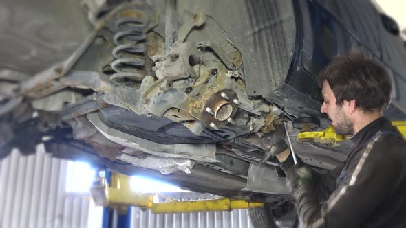 Mechanics Removing Worn Broken Car Parts in Garage Under the Automobile.