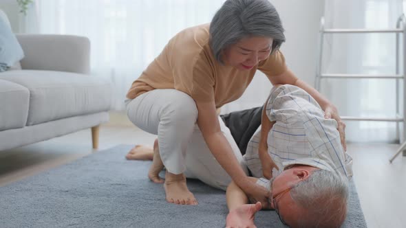 Asian senior wife helping elderly husband from falling on the ground. alt