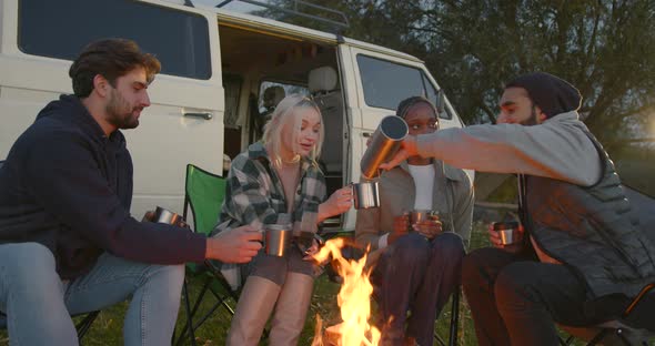 Four Tourists Warm Their Hands By the Fire at the Autumn Camp alt