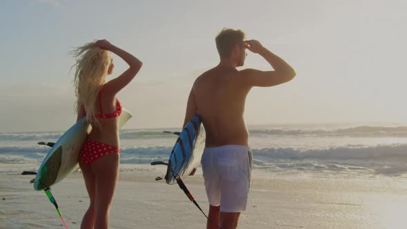 Couple standing with surfboard on the beach 
