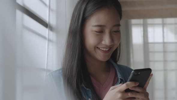 Portrait smiling young Asian businesswoman holding typing mobile phone.