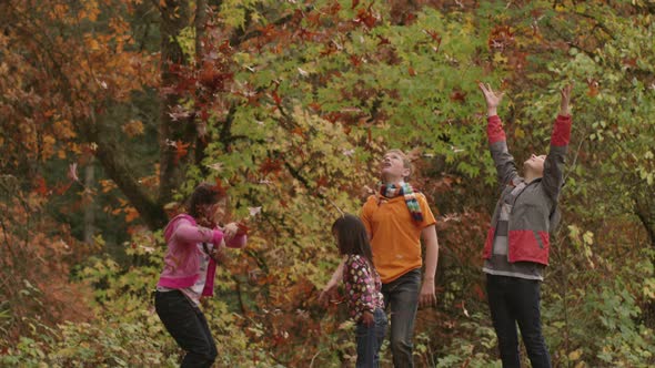 Group of kids in Fall throwing leaves