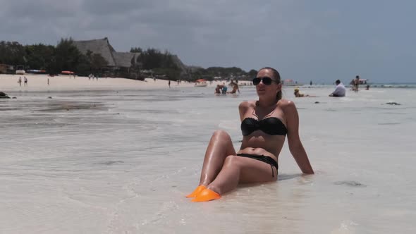 Young Woman in Black Bikini Tans on a Paradise White Sandy Beach Lies By Ocean