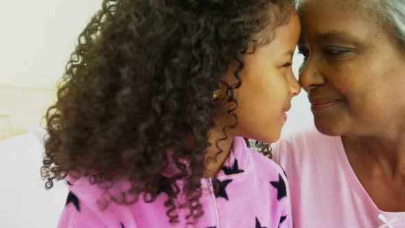 Smiling granddaughter and grandmother rubbing noses on bed 4k alt