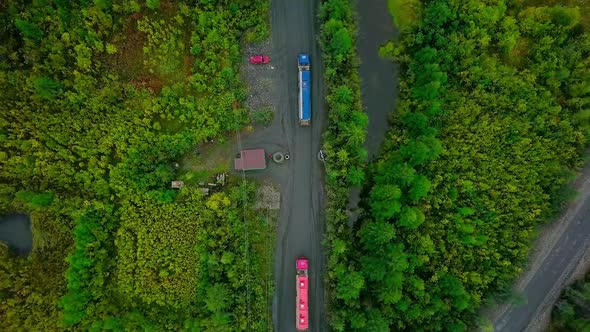 Red And Blue Transport Trucks Moving Valuable Minerals Through Forest Area alt
