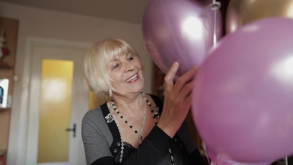 Cute Grandma Celebrates Her Birthday. Holds Multicolored Balloons in Her Hands alt