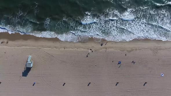 Birds eye view of waves on beach moving higher and upwards away from the beach revealing more of the alt