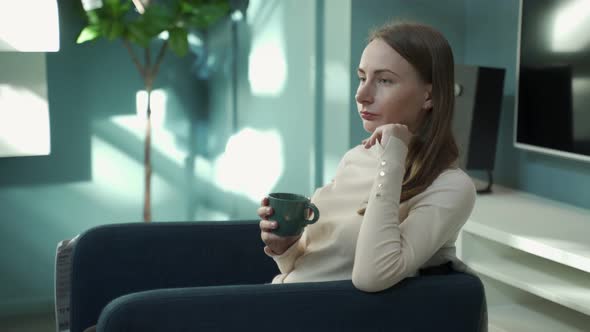 Woman at Home Sitting on Chair Relaxing Drinking Coffee or Tea alt