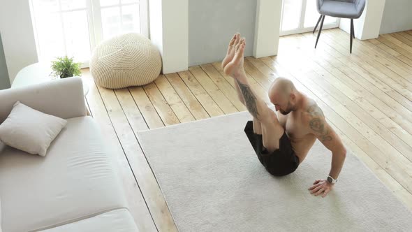 Muscular Man Is Doing Abs Exercises Crunches at Home Pulls His Legs To Chest alt