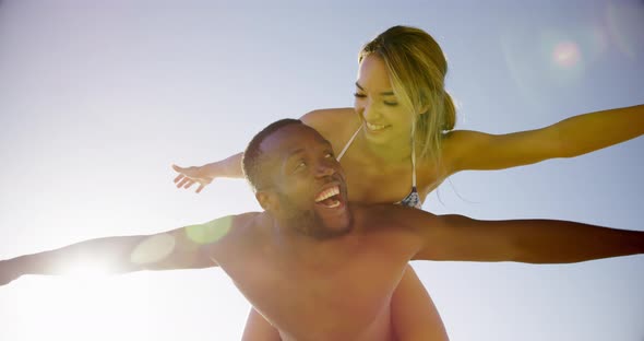 Man giving piggyback ride to woman on the beach 4k