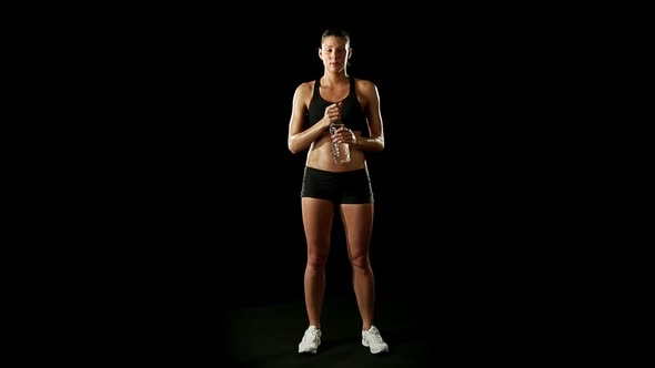 Young Athletic Woman Wearing Sporstwear is Drinking Water From Plastic Bottle Slow Motion Isolated