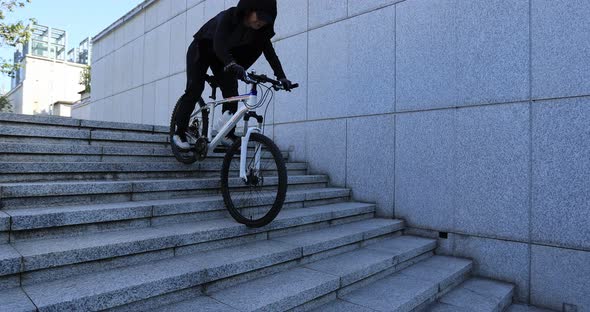 Woman free rider riding bike going down city stairs, slow motion alt
