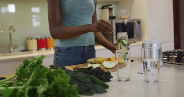 Midsectin of african american attractive woman preparing smoothie in kitchen alt