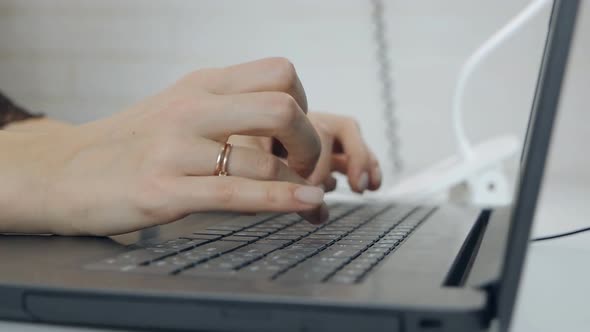 Hands Writing Ond a Keyboard of a Laptop or a Notebook in Home Office
