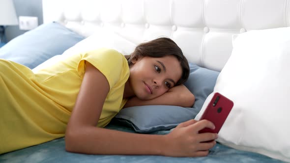 Smiling Child Texting on Smartphone in Bed Blogger