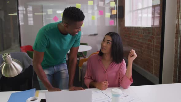 Diverse male and female business colleagues in discussion in meeting room analyzing documents alt