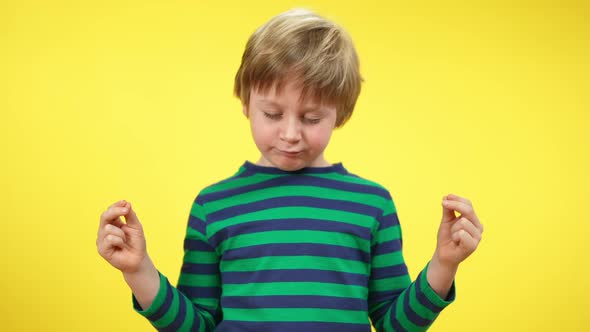 Charming Cute Kid Closing Eyes and Meditating at Yellow Background alt