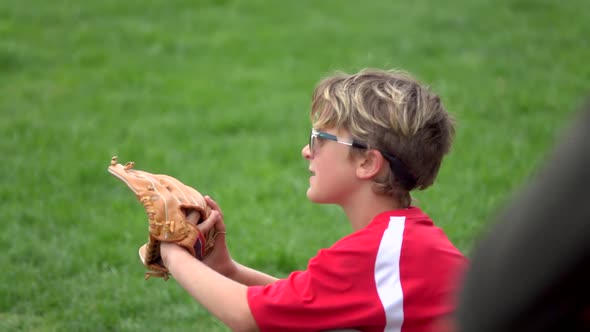 A boy practices playing catch on a little league baseball field. alt