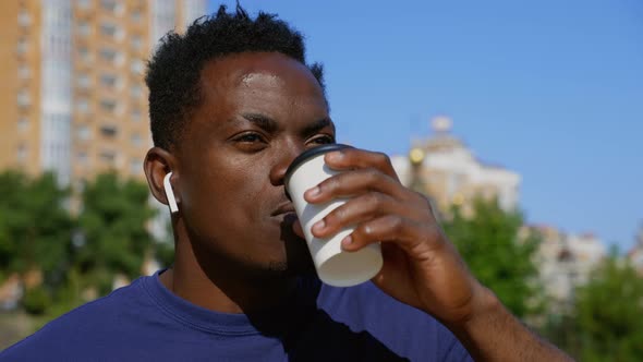 Close Up Afroamerican Man Freelancer Wearing Wireless Headphones Drinks Coffee alt