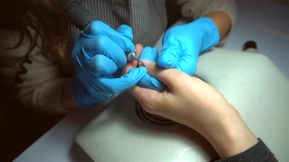 Close up footage of professional nail file drill in action finger nail treatment	 alt