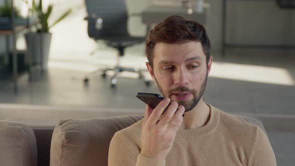 Young man recording voice recognition message on speakerphone alt