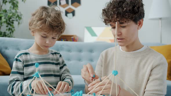 Clever Kid Doing Craft with Mother Talking and Making Play Dough Design at Home alt