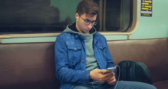 Fashionable Brutal Guy in Glasses and Headphones Rides in an Empty Subway Car alt