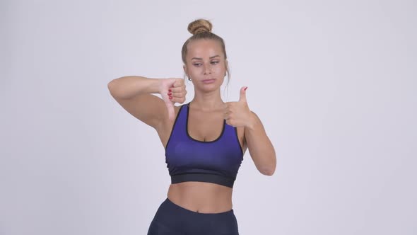 Young Beautiful Blonde Woman Choosing Between Thumbs Up and Thumbs Down alt