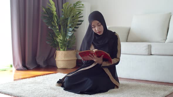 Young Muslim female wearing Islamic clothes reading the Quran