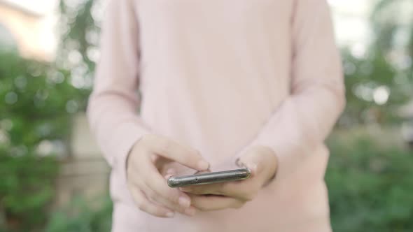 Asian tourist blogger woman using touchscreen technology at smartphone while walking