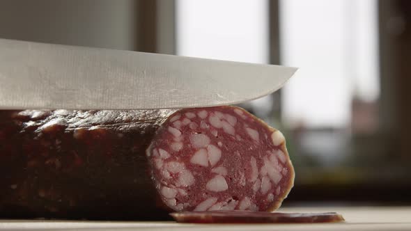 Cutting Sausage With A Knife A Closeup Of Hands And Kitchen On The Background alt