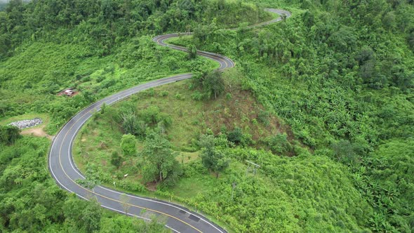 Aerial view of mountain road through tropical forest in countryside of Asia by drone